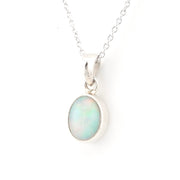 A silver pendant necklace featuring an oval opal stone with iridescent white, pale green, and blue play-of-color, set in a polished silver bezel on a delicate silver chain against a white background.