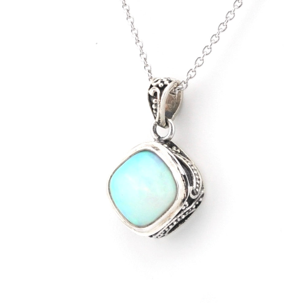 A silver pendant necklace featuring a square-shaped light blue opal stone in an ornate, textured silver bezel setting, suspended from a delicate silver chain against a plain white background.
