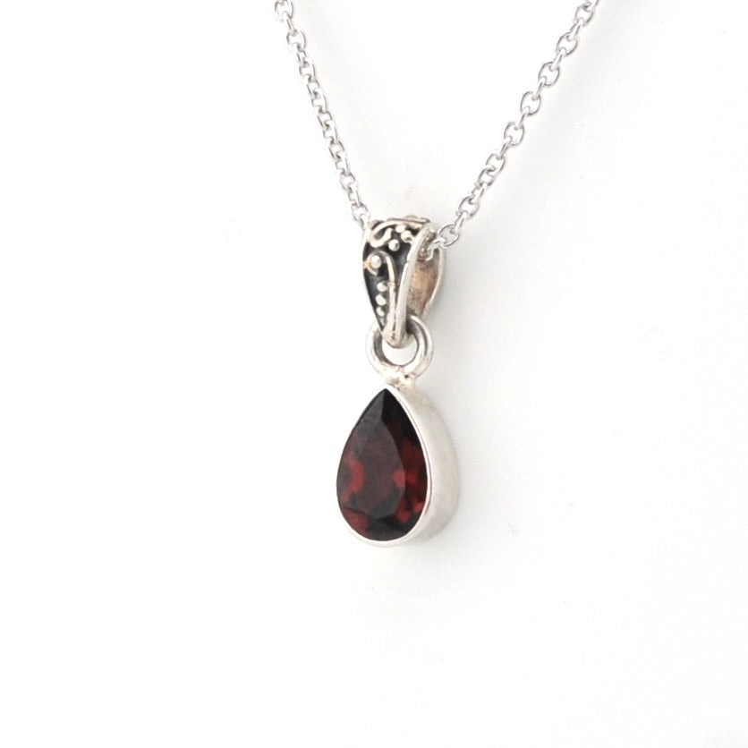 A silver teardrop pendant necklace featuring a dark red gemstone, shown on a clean white background.