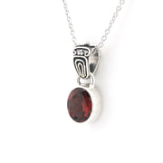 A silver pendant necklace featuring a polished oval red gemstone and an ornate silver bail, shown against a plain white background.