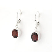 A pair of silver leverback earrings with oval dark red garnet gemstones, shown on a plain white background.