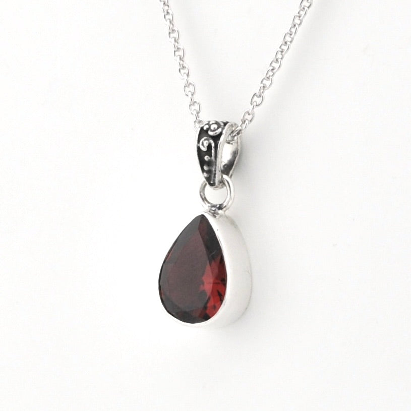A silver teardrop pendant necklace featuring a faceted dark red gemstone, shown on a clean white background.
