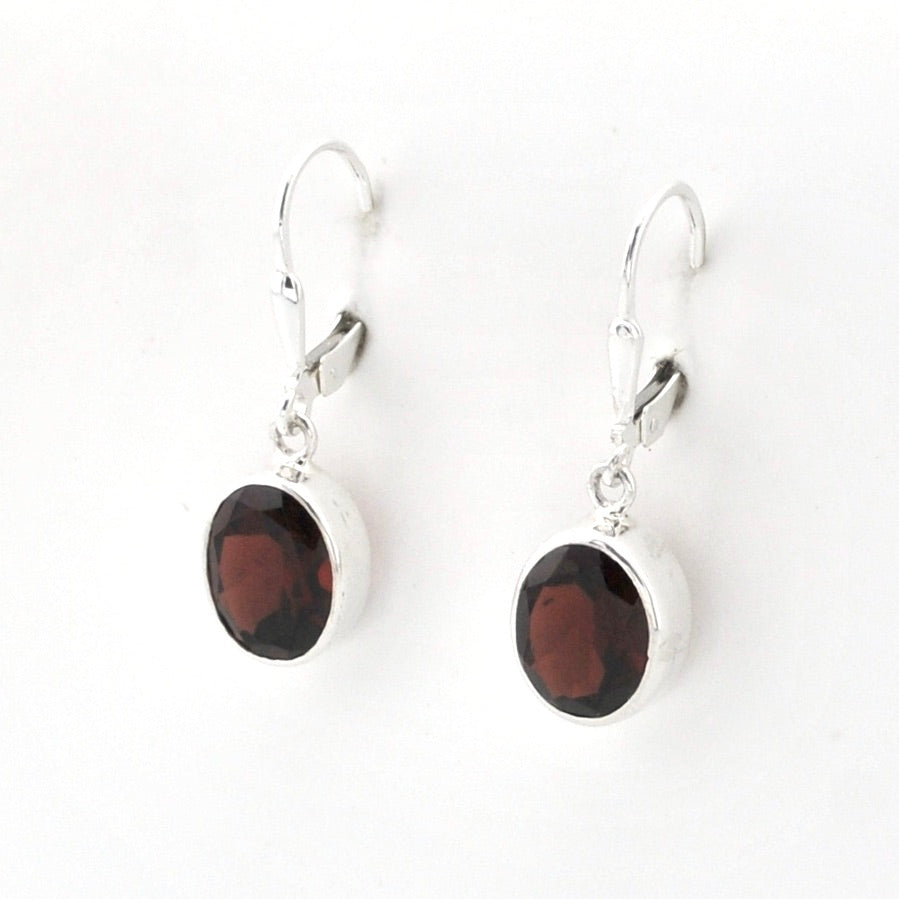 A pair of silver leverback drop earrings featuring oval dark reddish-brown gemstone charms, displayed on a clean white background.