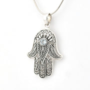 Silver Hamsa hand pendant with a clear gemstone on a white background