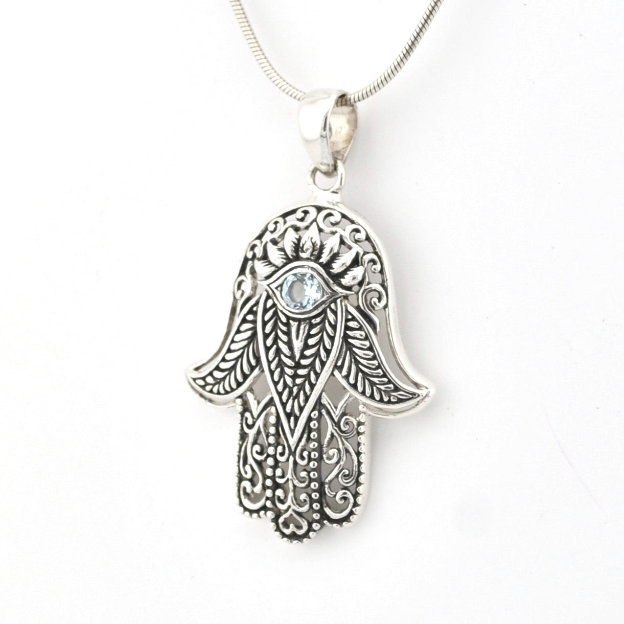 Silver Hamsa hand pendant with a clear gemstone on a white background