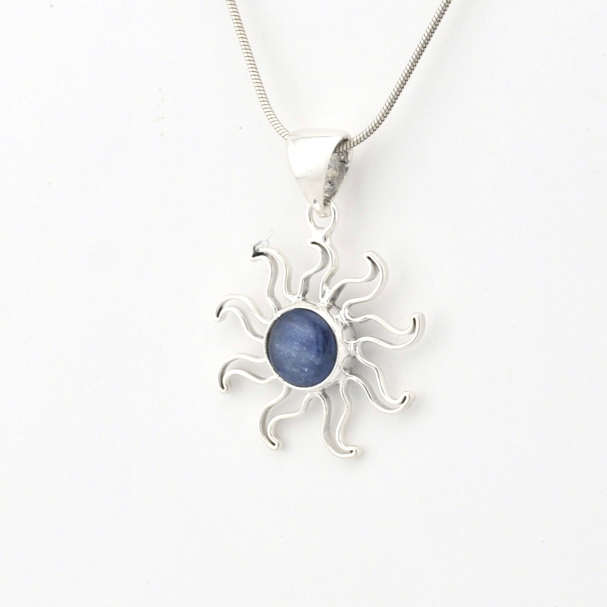 Silver sun-shaped pendant with a blue stone on a white background