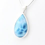 A teardrop-shaped pendant necklace featuring a marbled light blue and white stone in a polished silver bezel setting, suspended from a silver snake chain against a plain white background.