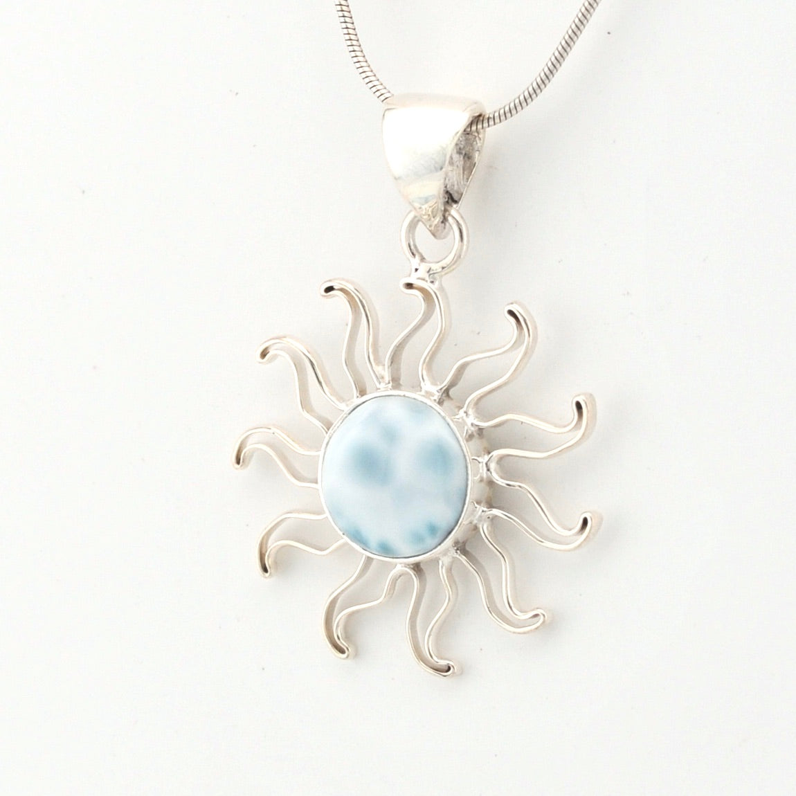 Silver sun-shaped pendant with a blue center on a white background