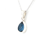 A silver teardrop pendant necklace featuring a faceted dark blue gemstone, shown on a clean white background.