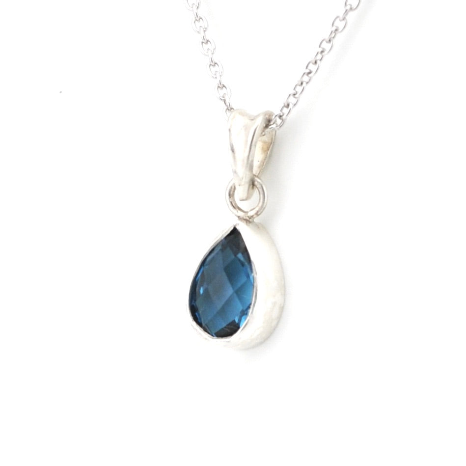 A silver teardrop pendant necklace featuring a faceted dark blue gemstone, shown on a clean white background.