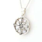 A sterling silver compass pendant necklace on a delicate silver chain, shown against a plain white background.