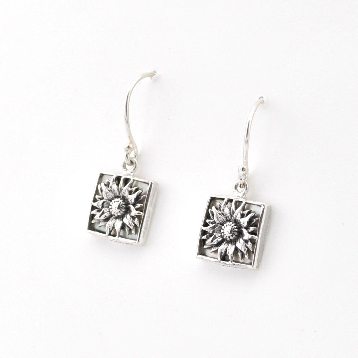 Silver earrings with floral designs on a white background