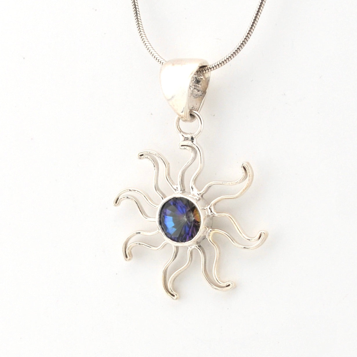 Silver sun-shaped pendant with a blue gemstone on a white background