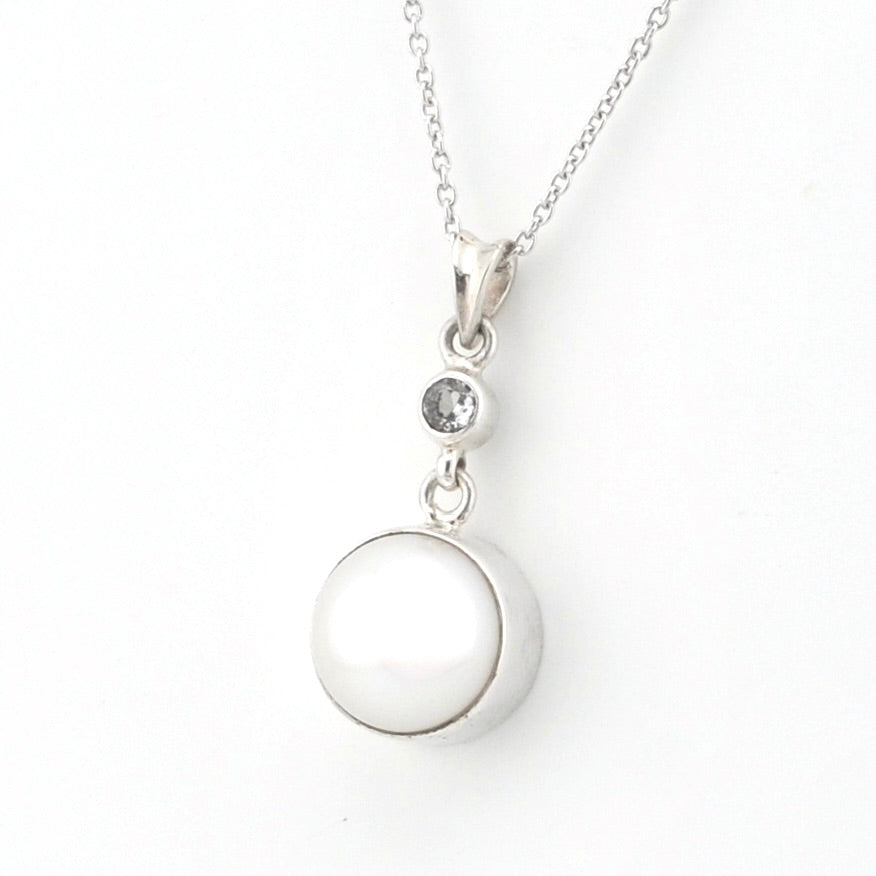 A silver pendant necklace featuring a large, smooth white oval pearl and a small clear round gemstone, shown on a delicate silver chain against a plain white background.