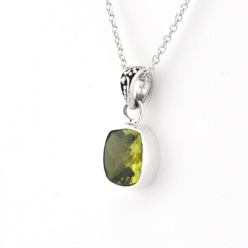 A silver pendant necklace featuring a cushion-cut olive green gemstone in a polished silver bezel setting, suspended from a delicate silver chain against a plain white background.