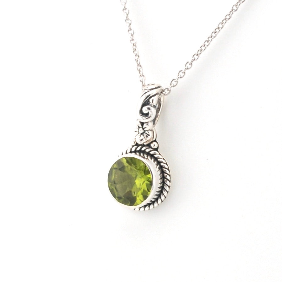 Silver necklace with a green peridot pendant on a white background
