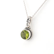 Silver necklace with a green peridot pendant on a white background