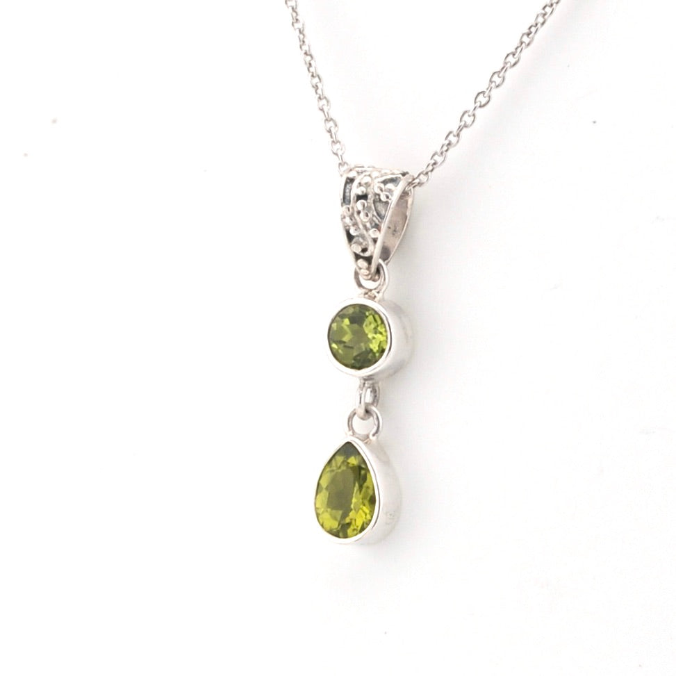 Silver necklace with two green gemstones on a white background