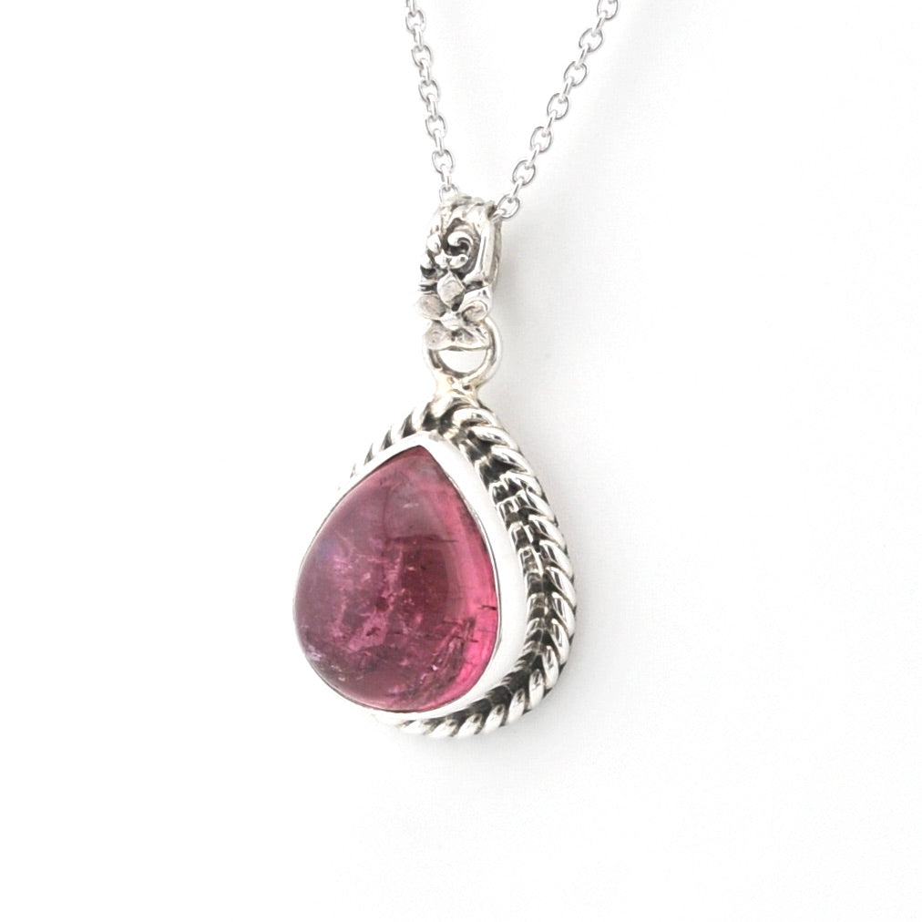 A silver teardrop pendant necklace featuring a faceted pink gemstone, set in a textured silver bezel with a matching silver chain, shown against a plain white background.