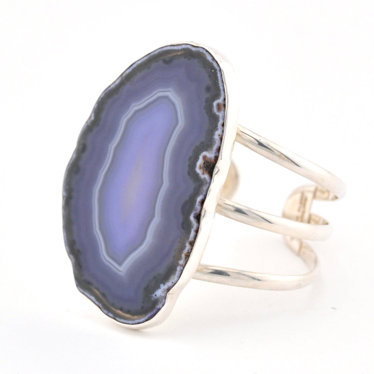 Silver cuff bracelet with a purple agate slice on a white background