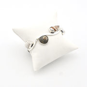 Silver shell bracelet on a white cushion against a white background