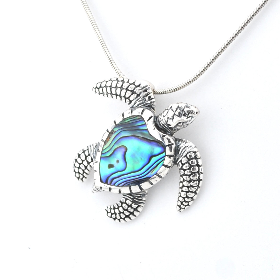 Turtle-shaped pendant with abalone shell inlay on a white background