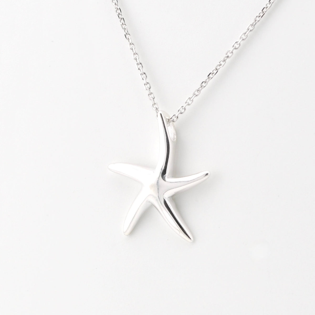 A silver starfish pendant necklace on a delicate silver chain, photographed against a clean white background.
