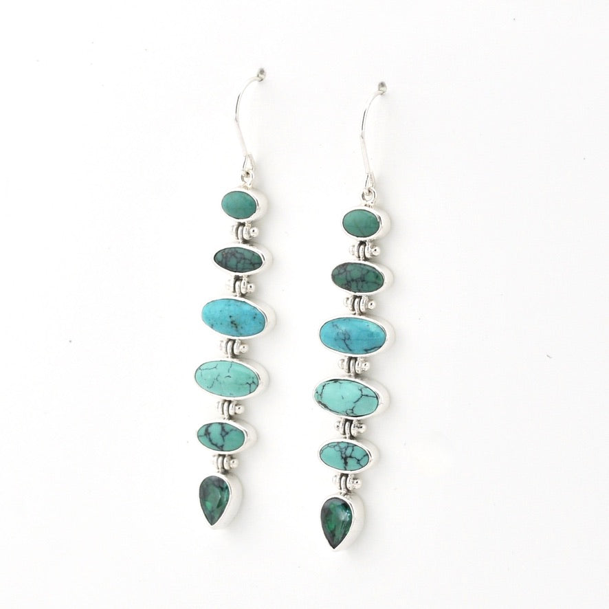 A pair of silver dangle earrings featuring a vertical stack of oval and teardrop-shaped turquoise and green stone beads, shown against a plain white background.