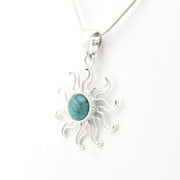A sterling silver sunburst pendant necklace featuring a central oval turquoise stone, shown on a clean white background.