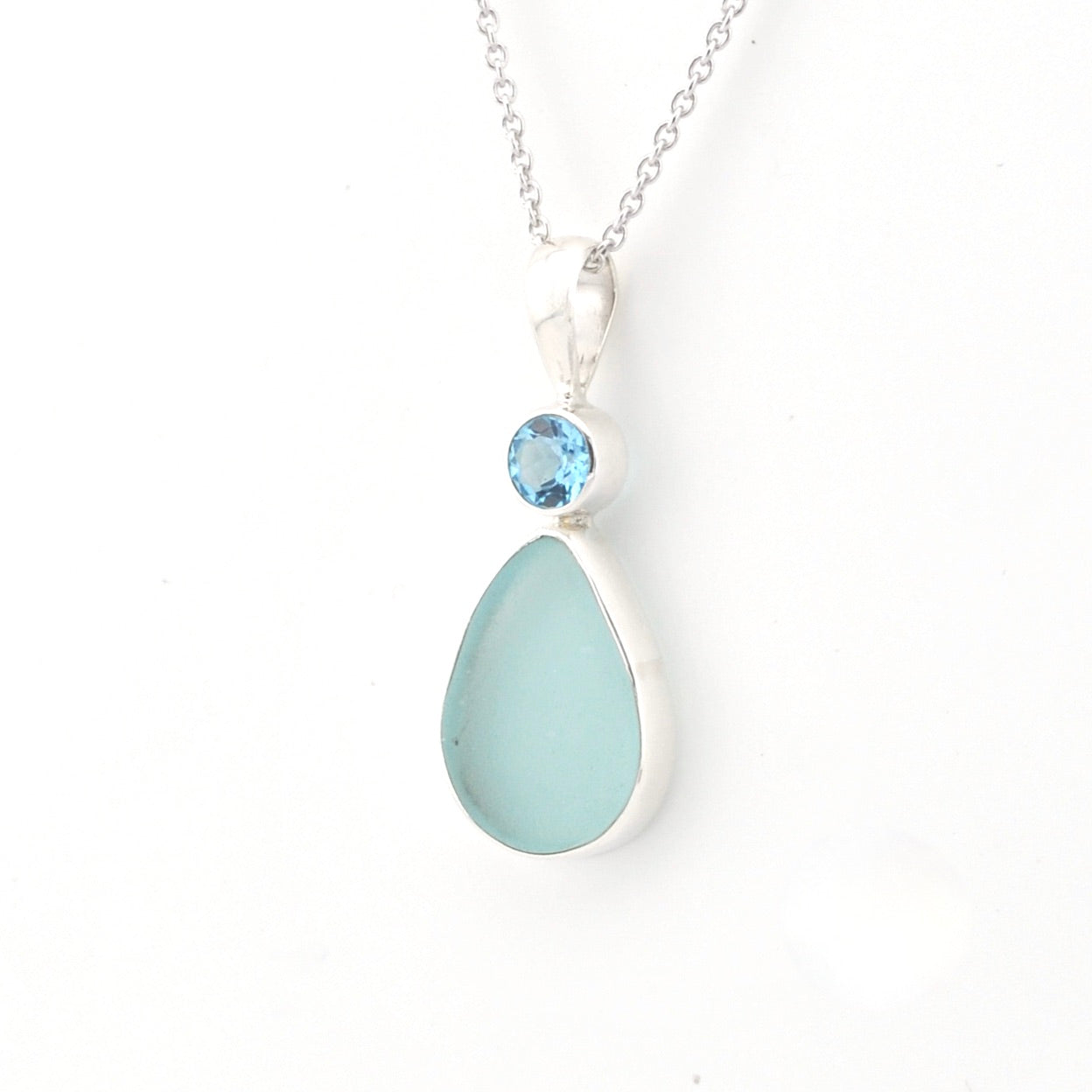 Necklace with a teardrop-shaped light blue pendant and a smaller round blue gemstone on a white background