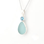 Necklace with a teardrop-shaped light blue pendant and a smaller round blue gemstone on a white background