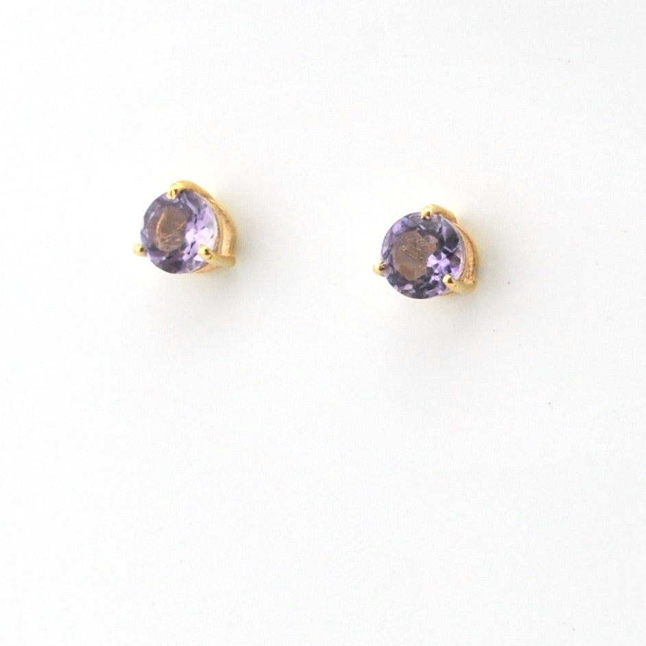 Pair of gold earrings with purple gemstones on a white background
