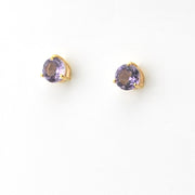Pair of gold earrings with purple gemstones on a white background