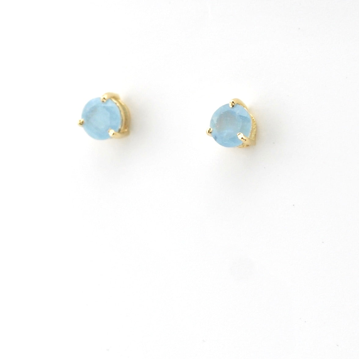 Pair of gold earrings with light blue gemstones on a white background