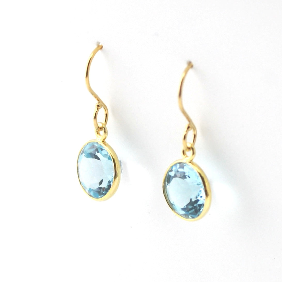 Gold earrings with blue gemstones on a white background