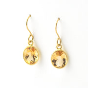 Gold earrings with yellow gemstones on a white background