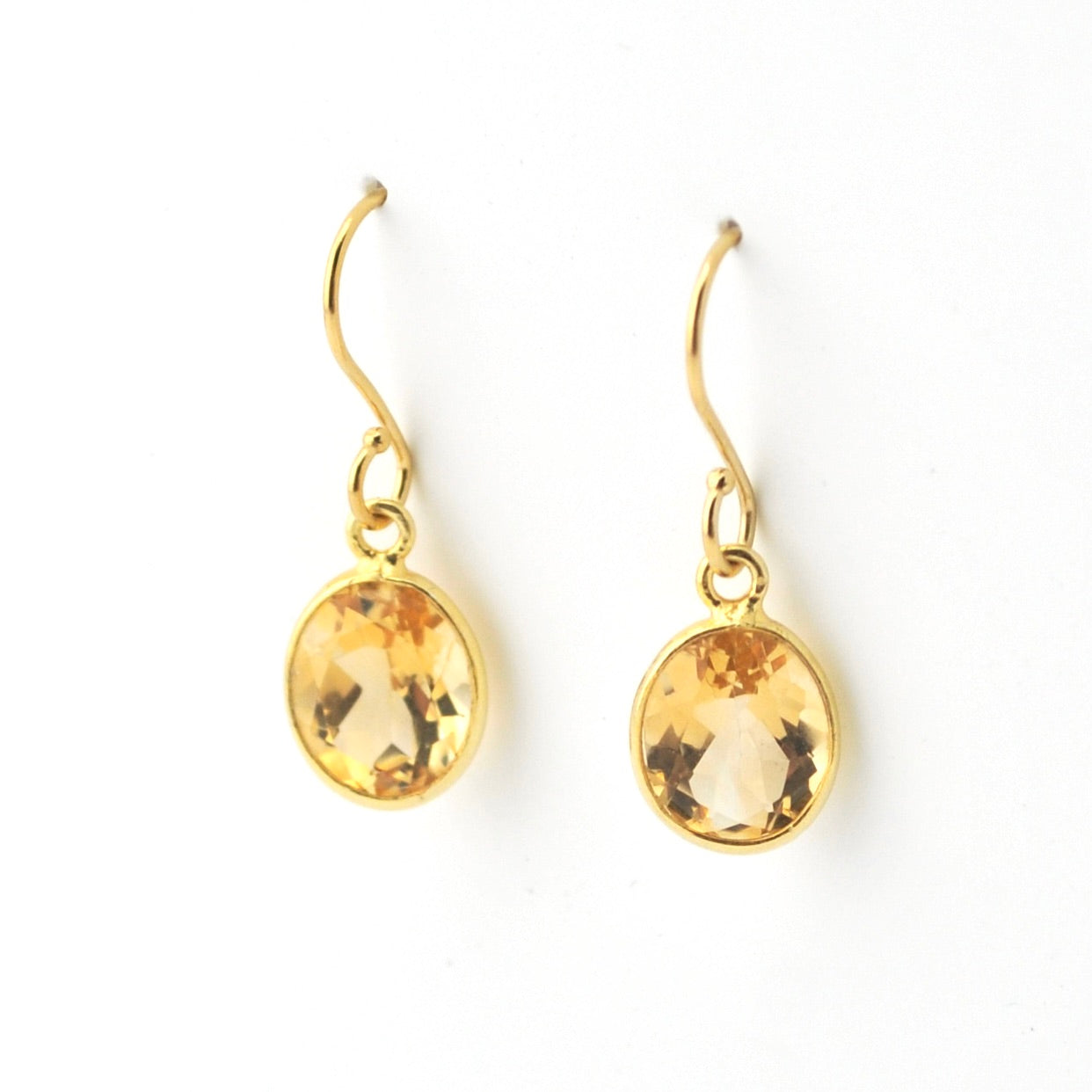 Gold earrings with yellow gemstones on a white background