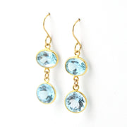 Gold earrings with blue gemstones on a white background