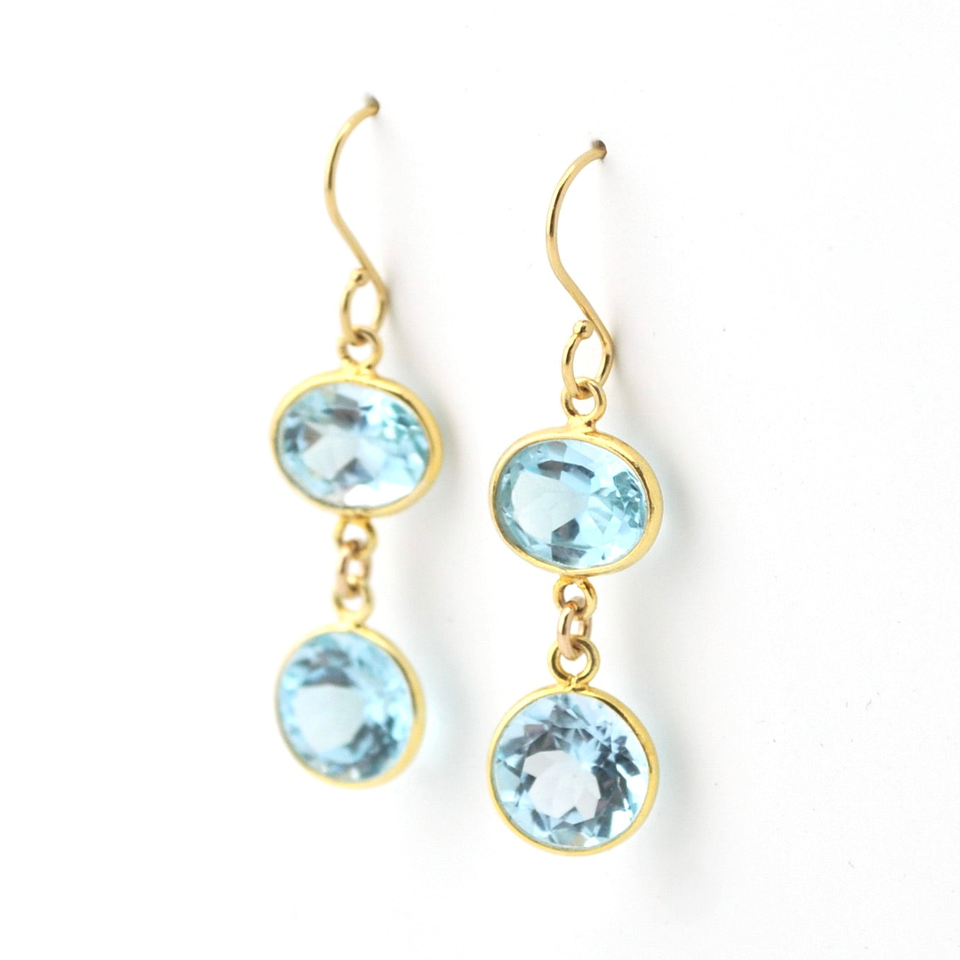 Gold earrings with blue gemstones on a white background