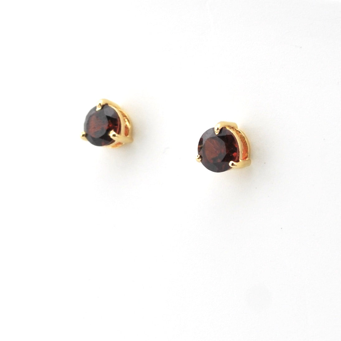 Pair of gold earrings with round gemstones on a white background