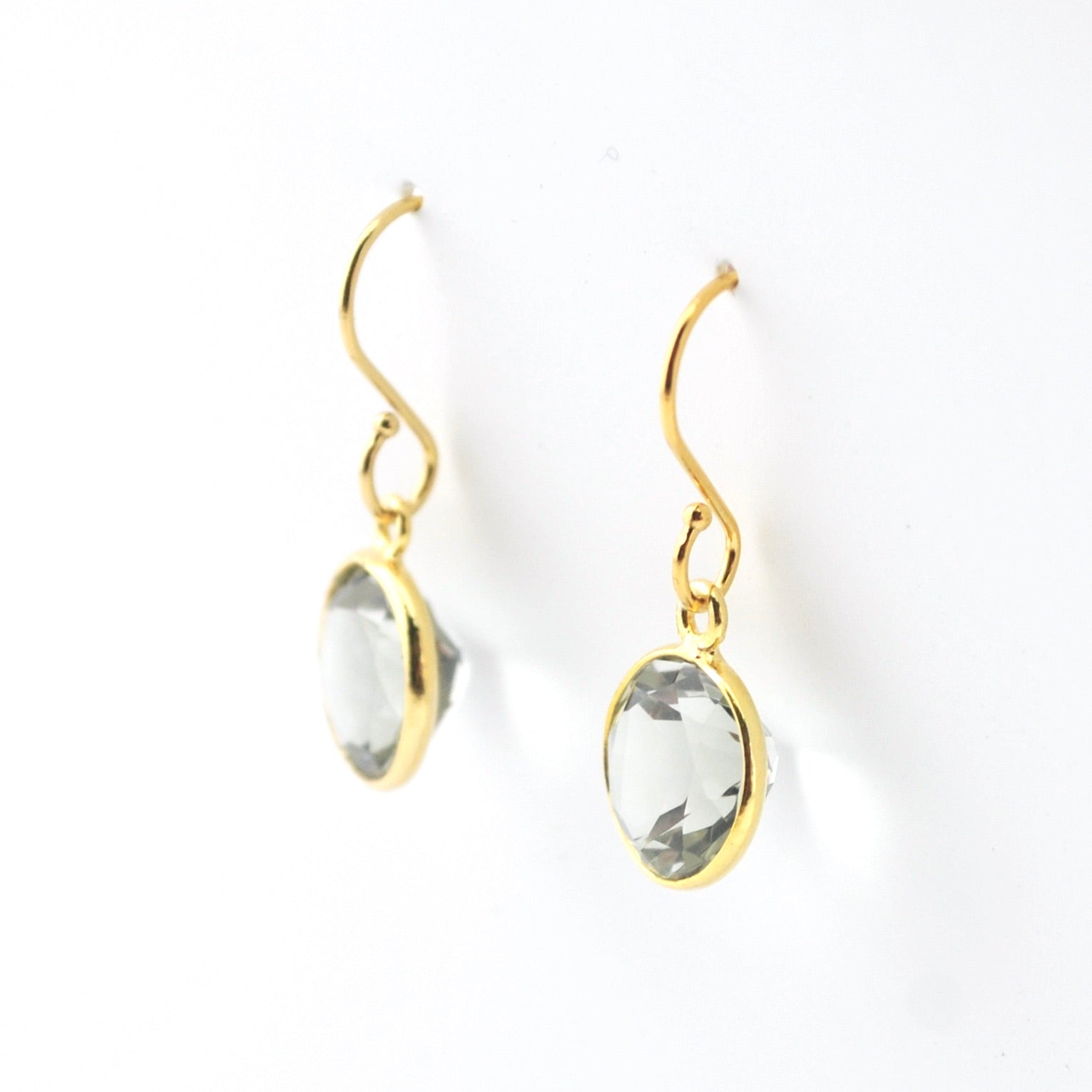 Gold earrings with clear gemstones on a white background