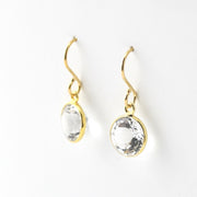 Gold earrings with clear gemstones on a white background