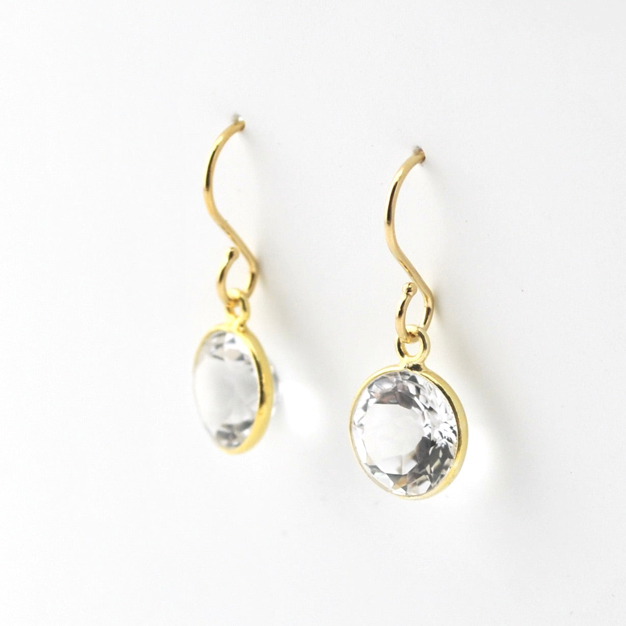 Gold earrings with clear gemstones on a white background