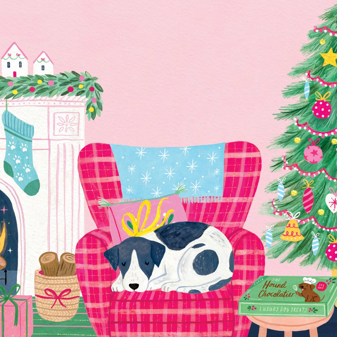 A cozy Christmas illustration featuring a black and white dog sleeping on a pink plaid armchair with a blue starry pillow. A pink Christmas tree stands on the right, a fireplace with a green stocking and mantel is on the left, and a small gift box labeled 'Hand Chocolates' sits on a table in the foreground against a soft pink background.