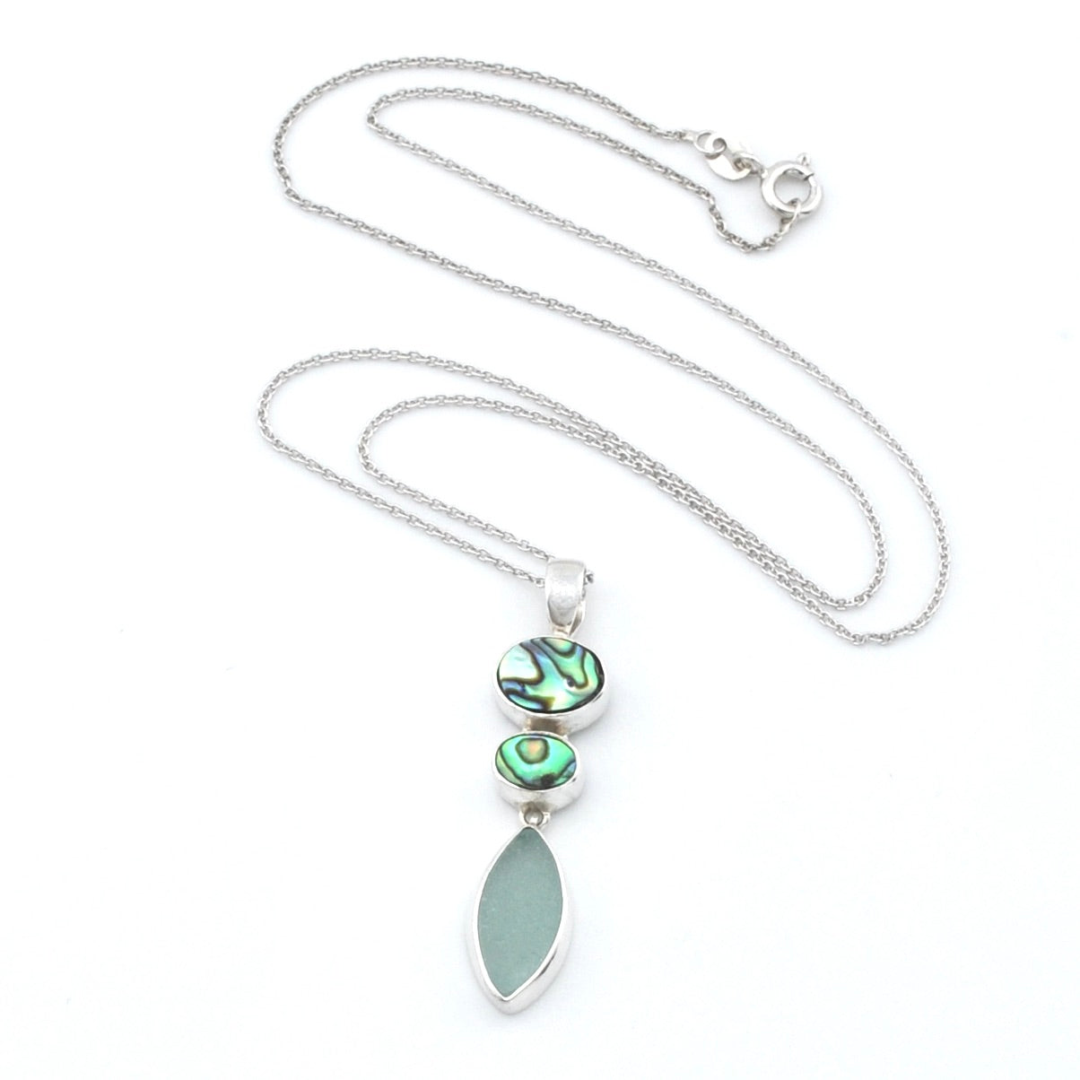 A silver necklace featuring a vertical pendant with two iridescent abalone stones and a large, smooth, light green teardrop-shaped sea glass, displayed on a white background.