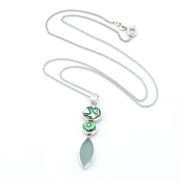 A silver necklace featuring a vertical pendant with two iridescent abalone stones and a large, smooth, light green teardrop-shaped sea glass, displayed on a white background.