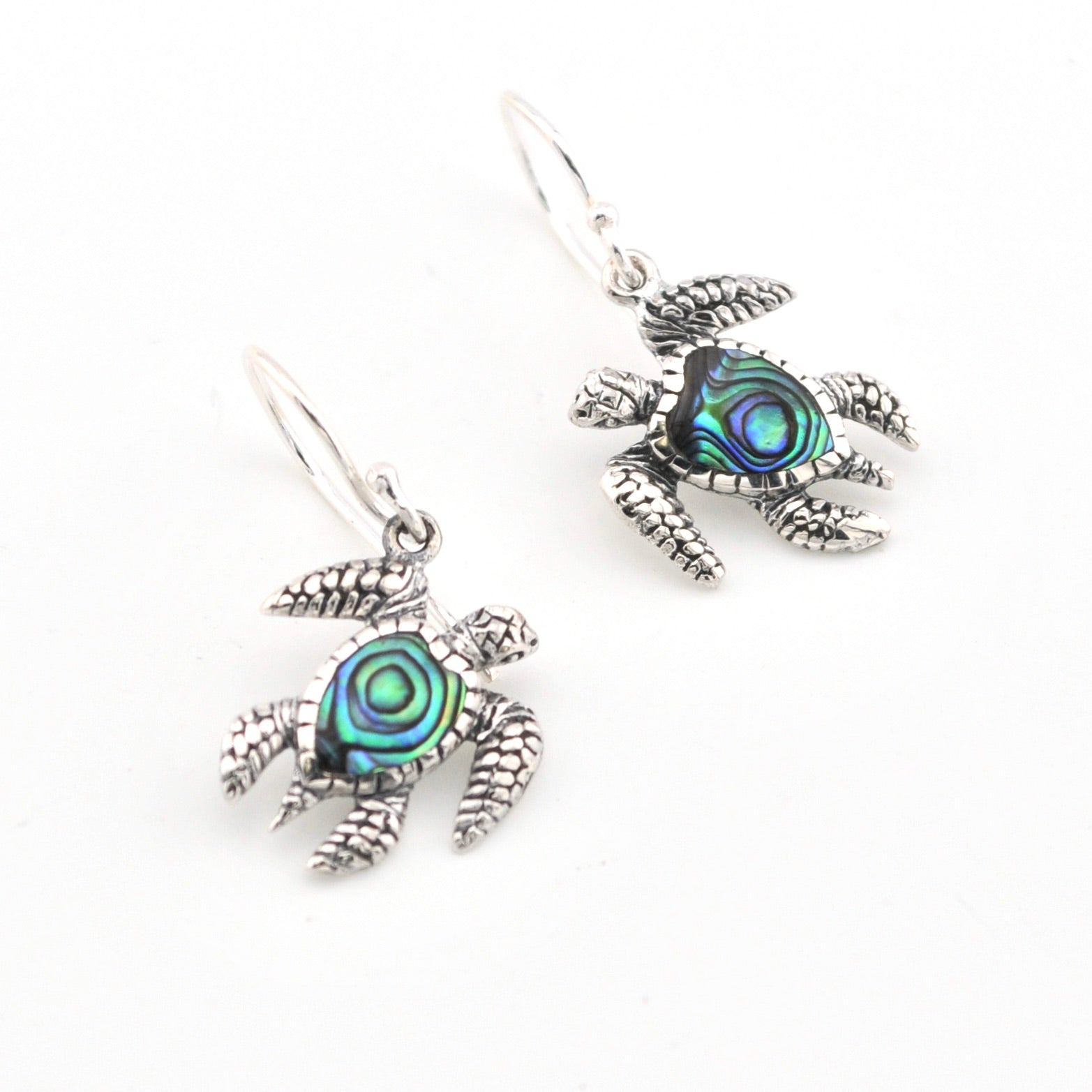 Silver turtle earrings with abalone shell centers on a white background