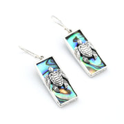 Pair of turtle earrings with abalone shell inlay on a white background