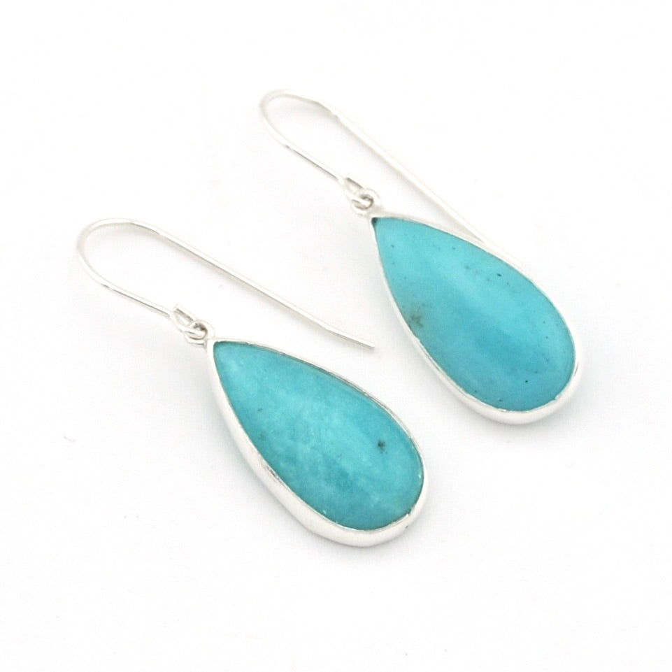 A pair of silver drop earrings featuring teardrop-shaped turquoise stones, displayed on a clean white background.