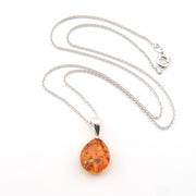 Amber teardrop pendant on a silver chain against a white background